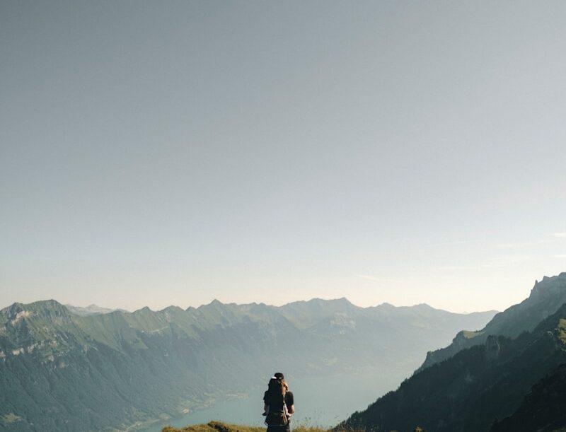 person hiking above mountain overlooking river