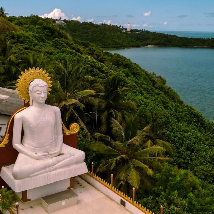 a statue of a person sitting on a bench by a body of water