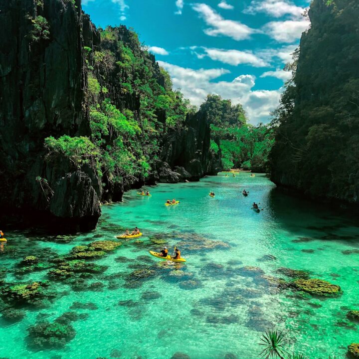 a group of people in a body of water surrounded by large rocks