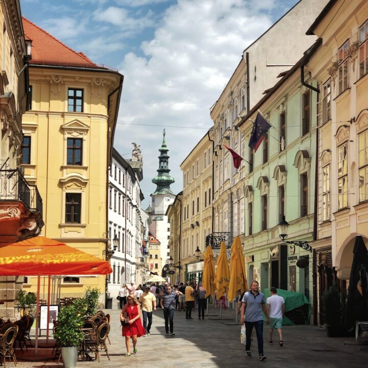 a group of people walking down a street next to tall buildings