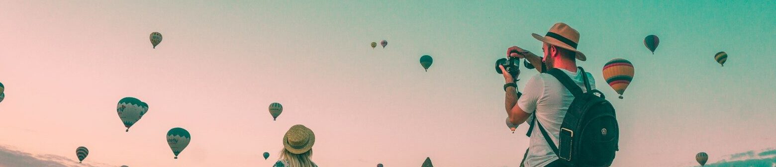 man taking photo of hot air balloons